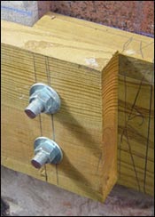 If the ledger board attaches to a brick house, you will likely either epoxy threaded rod into the masonry wall (shown here) or bolt completely through the brick.